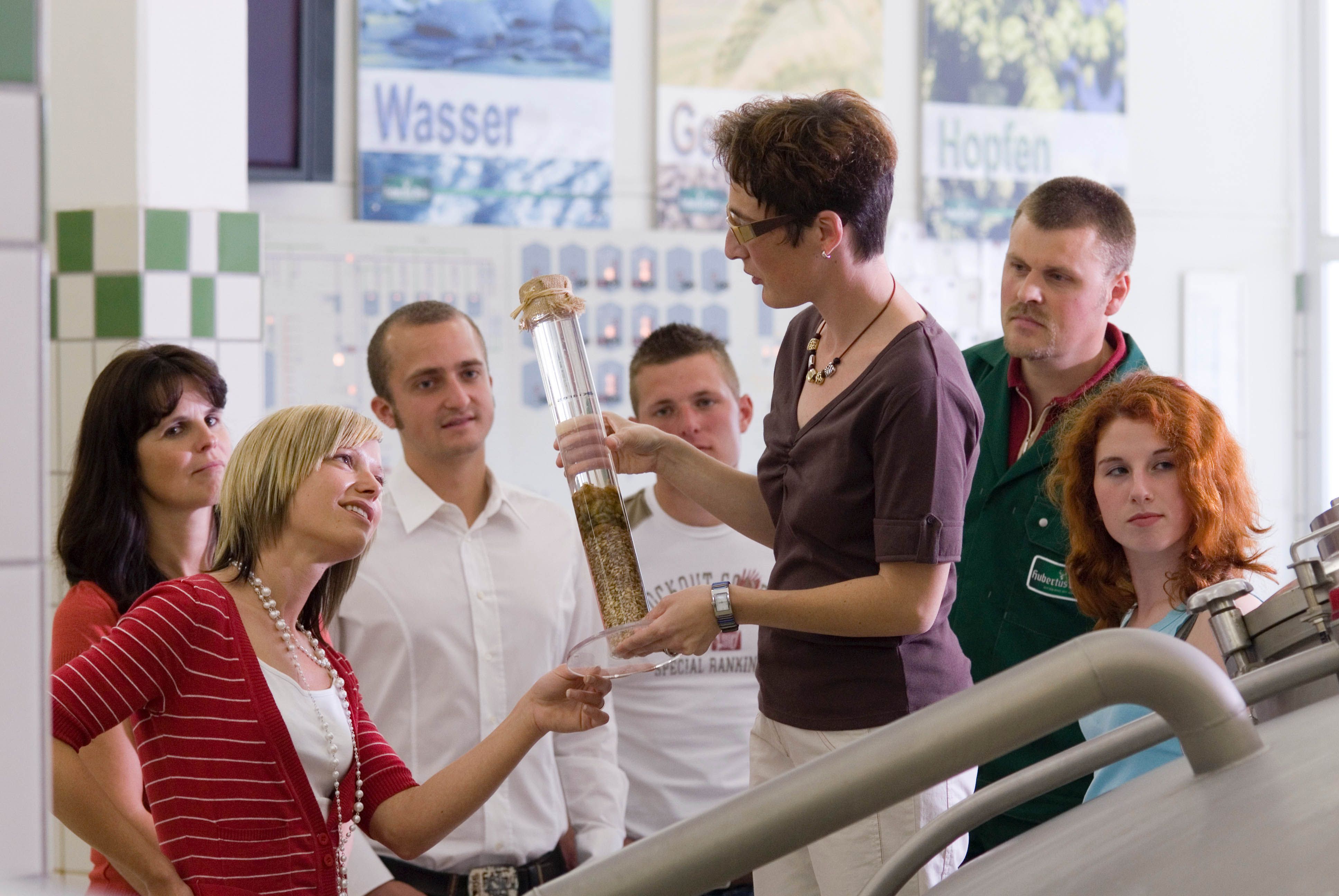 Skupina lidí na prohlídce pivovaru s průvodcem.