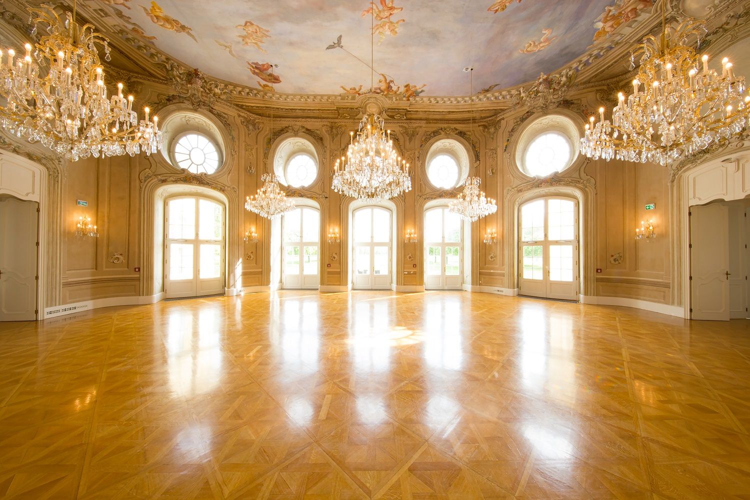 Elegantní taneční sál s lustry a malovaným stropem v Konferenčním centru Laxenburg.