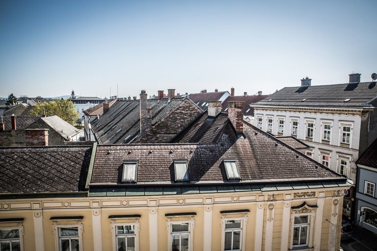 Ausblick auf Dächer der Nachbargebäude und blauem Himmel.