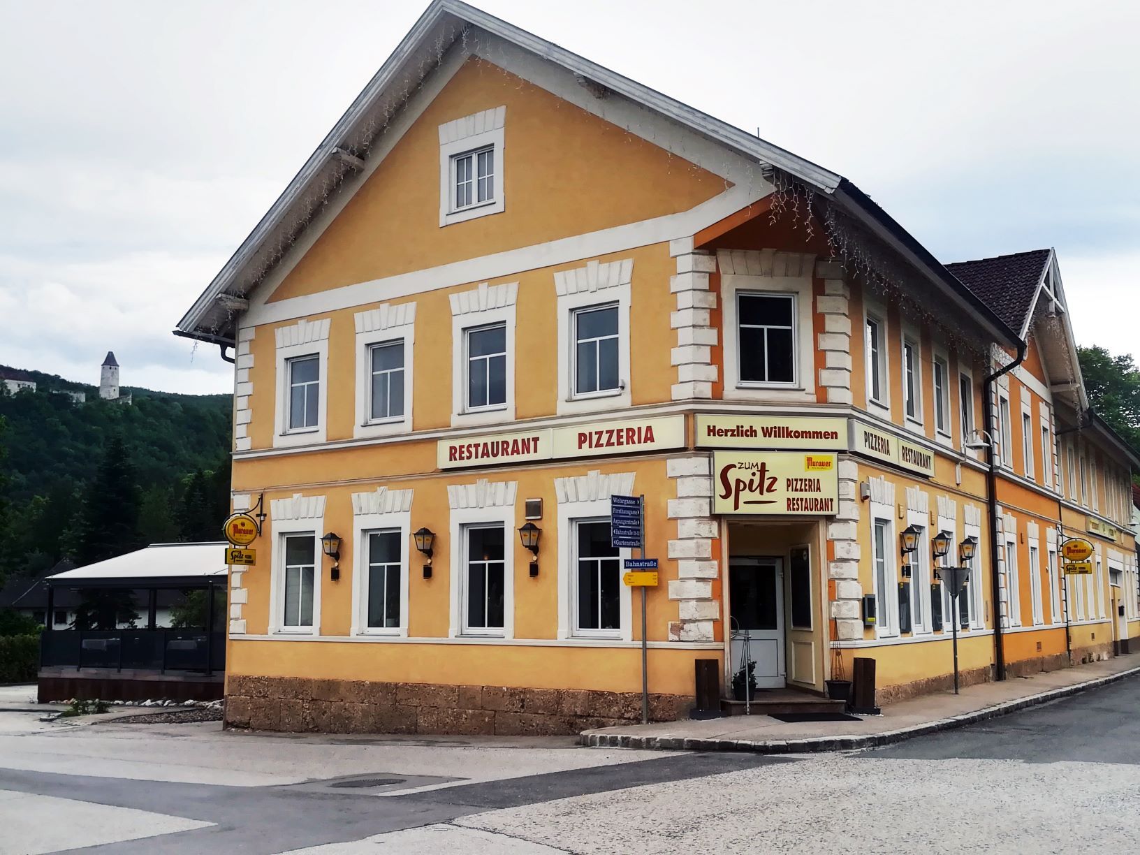 Žlutá budova s nápisem "Restaurant Pizzeria Zum Spitz".