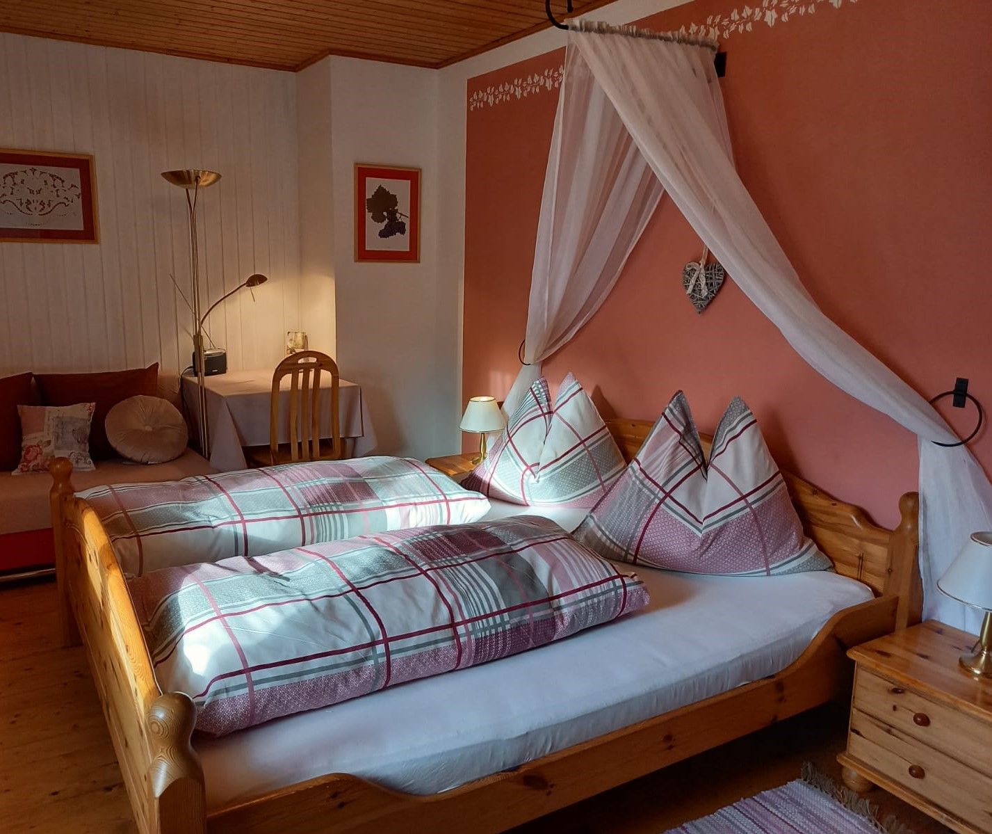 Útulný pokoj pro hosty s manželskou postelí, nočními lampičkami a psacím stolem.