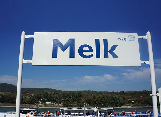 Značka s nápisem "Melk Nr. 8" na pozadí modré oblohy.