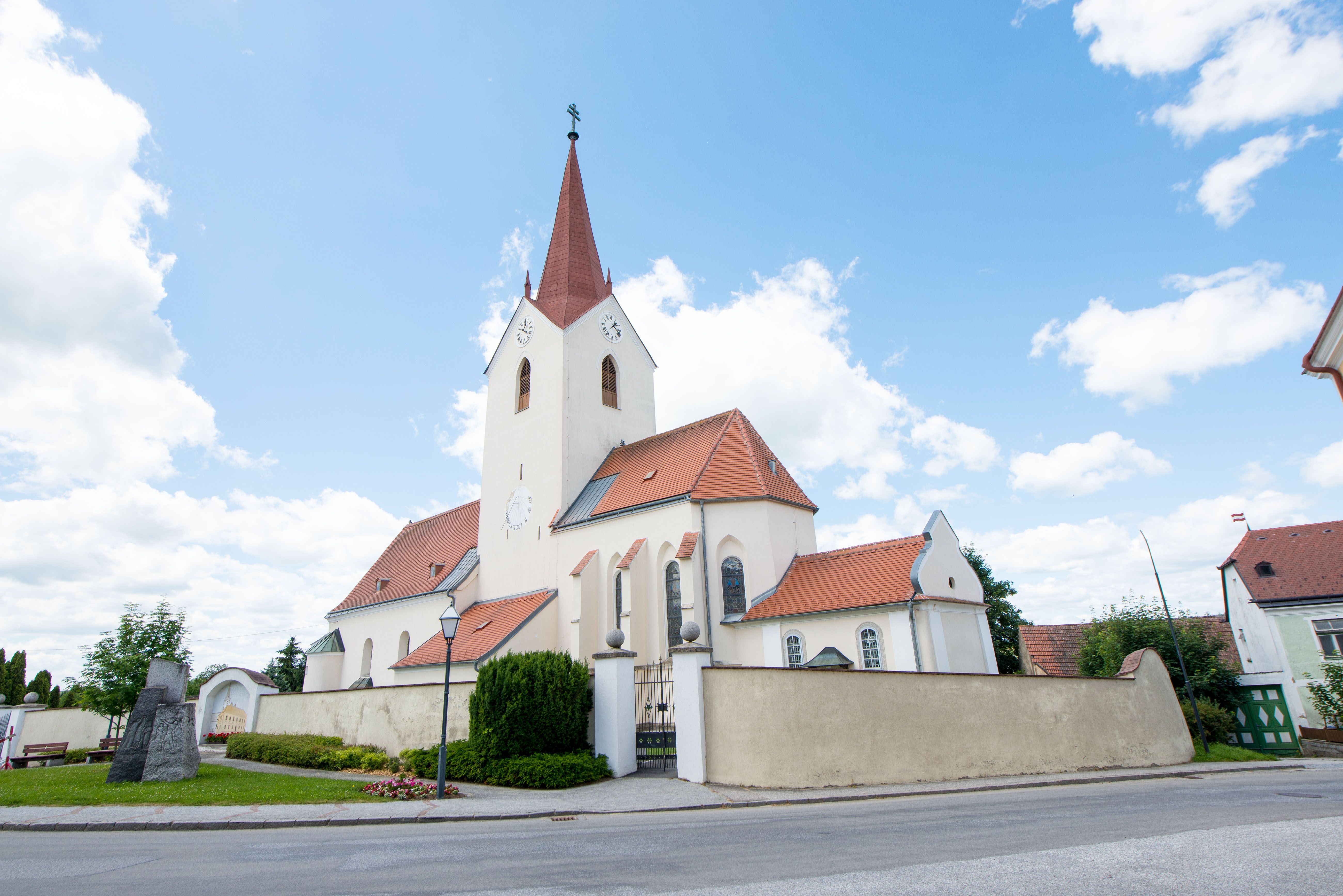 Kostel ve Schweiggers s červenou střechou a věží na pozadí modré oblohy.