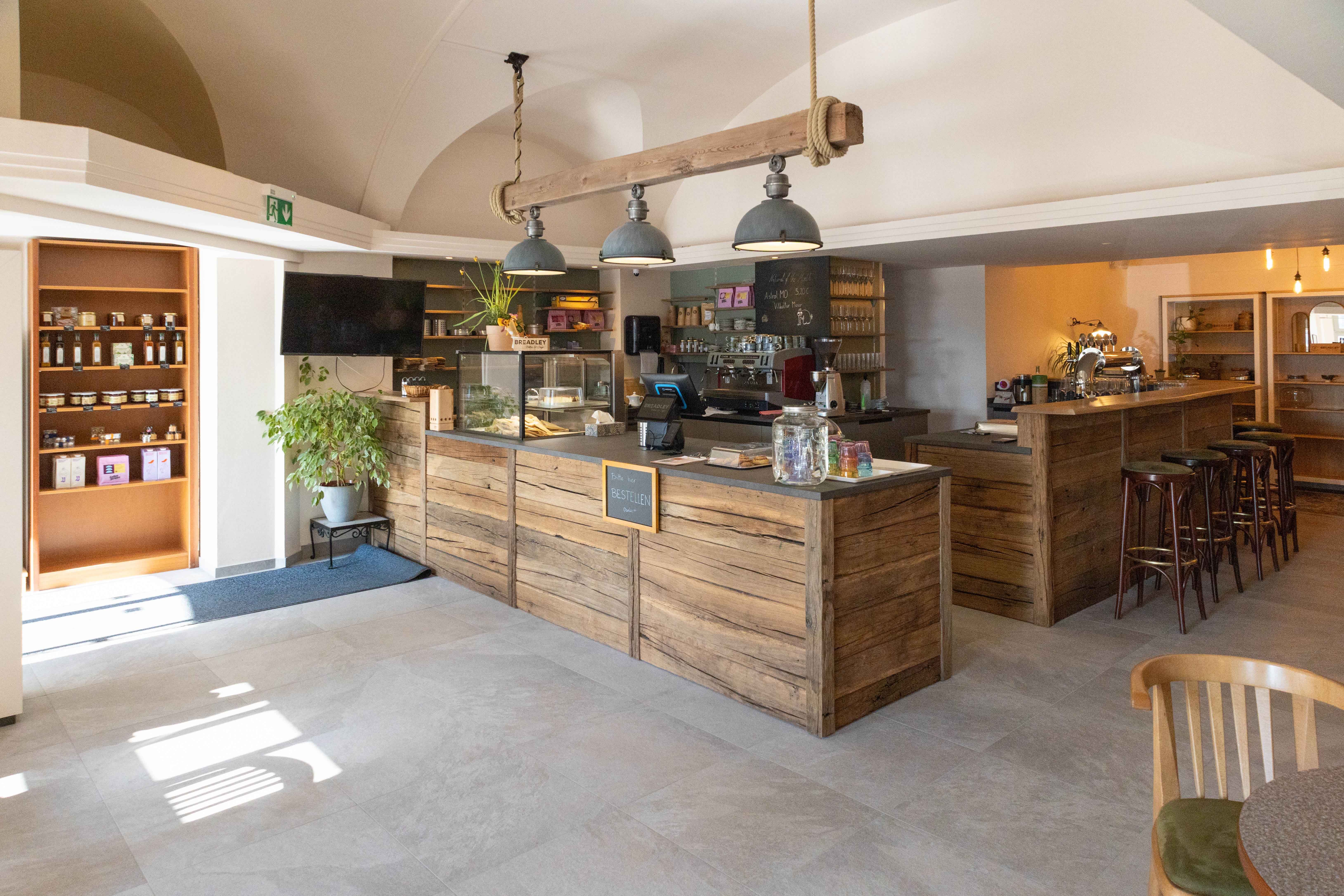 Pohled do interiéru útulné kavárny s dřevěným nábytkem a pultem.