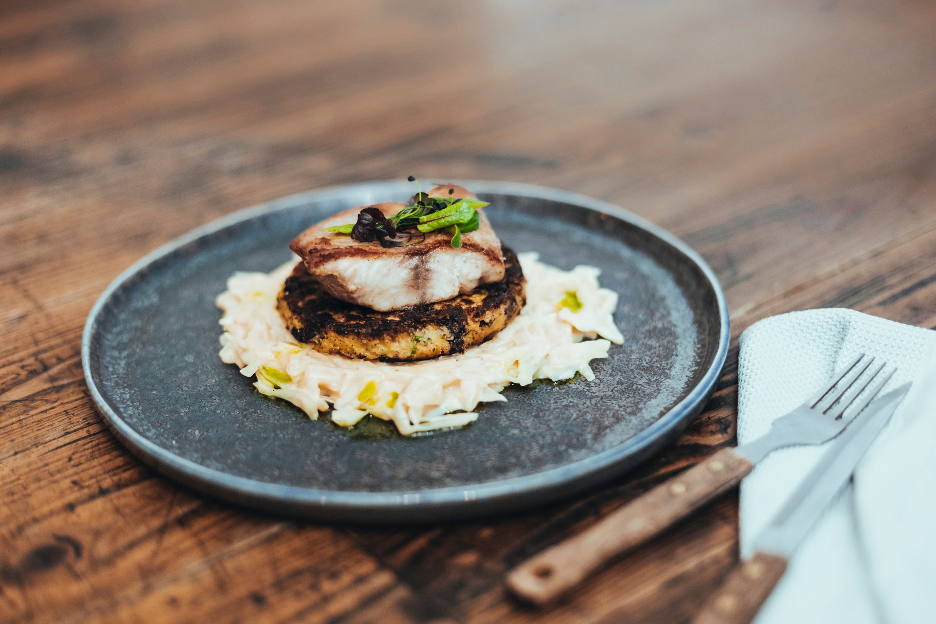 Pokrm s rybou na rösti a zelím na talíři.