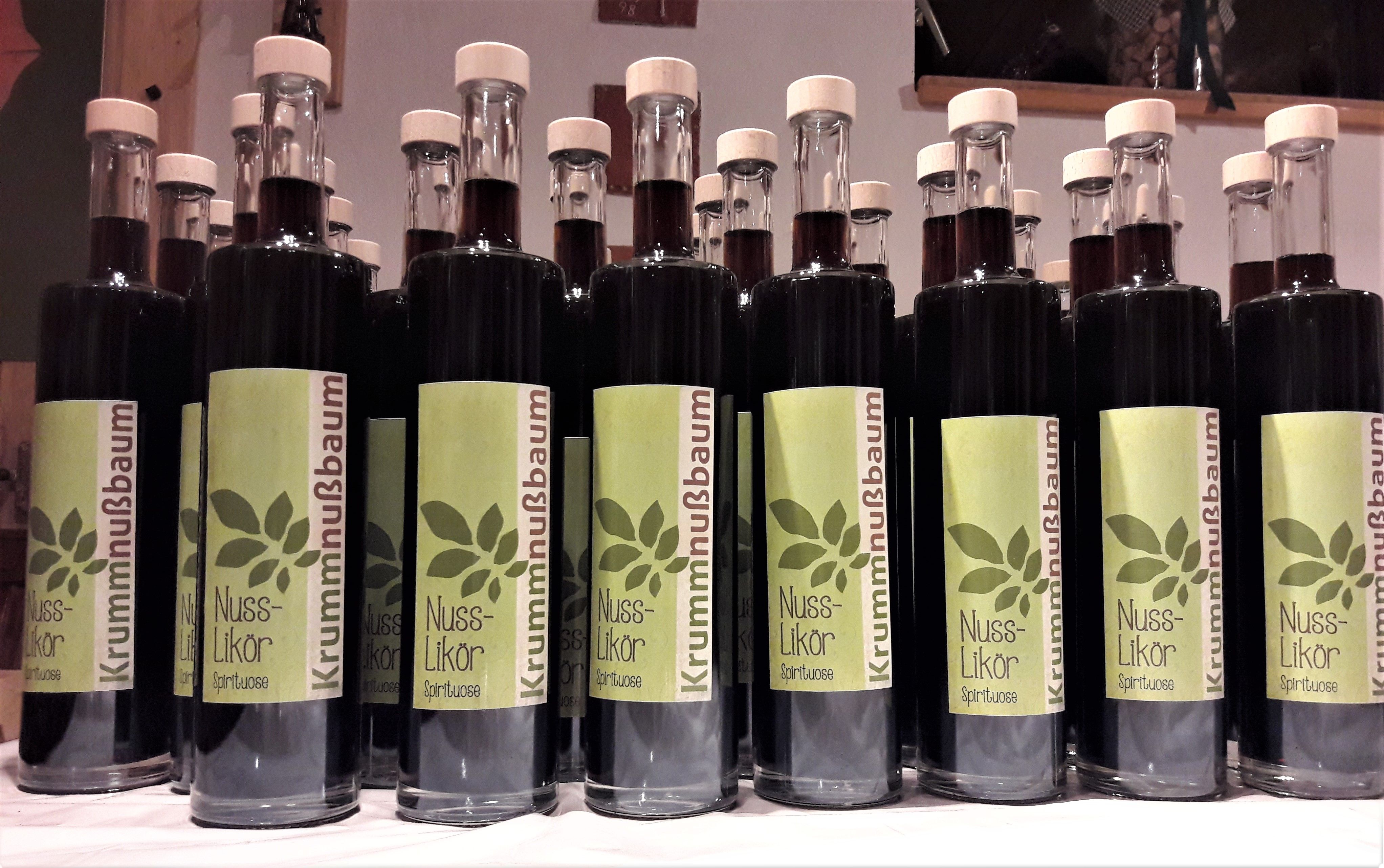 Řada lahví s ořechovým likérem a zelenými etiketami.