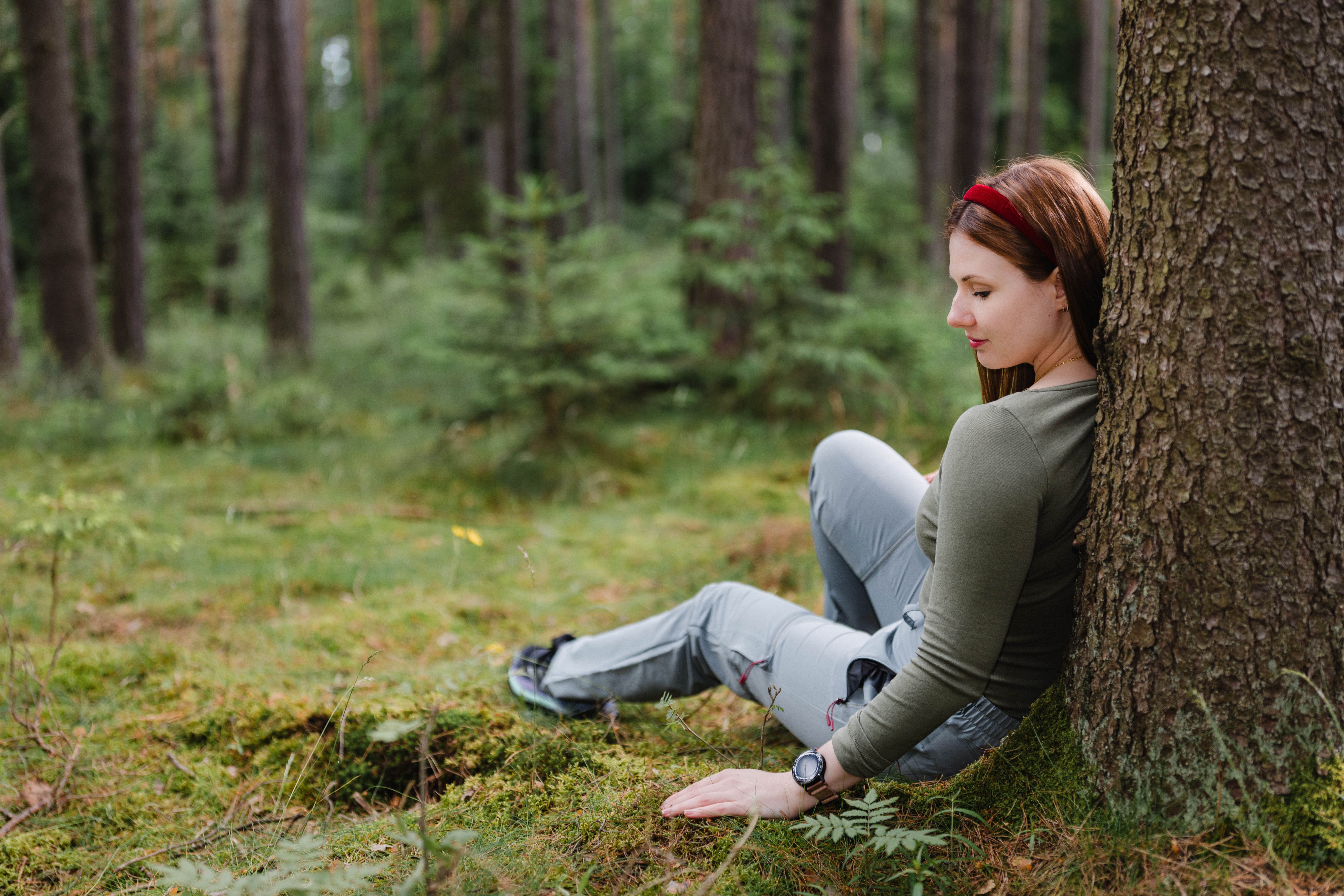 Žena opřená o strom v lese.