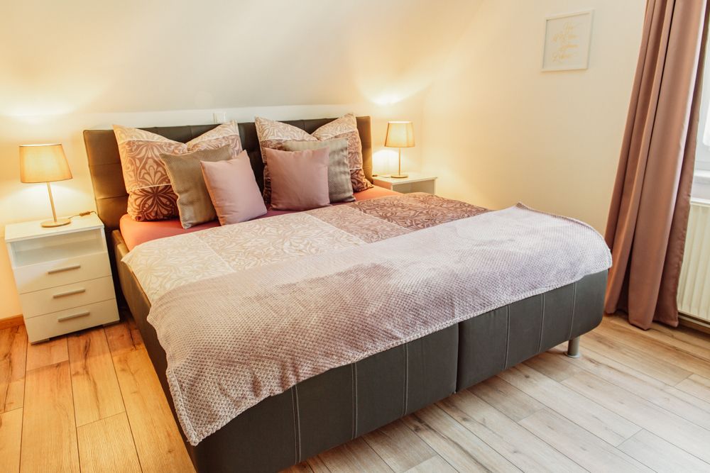 Útulná ložnice s manželskou postelí, nočními stolky a lampičkami.