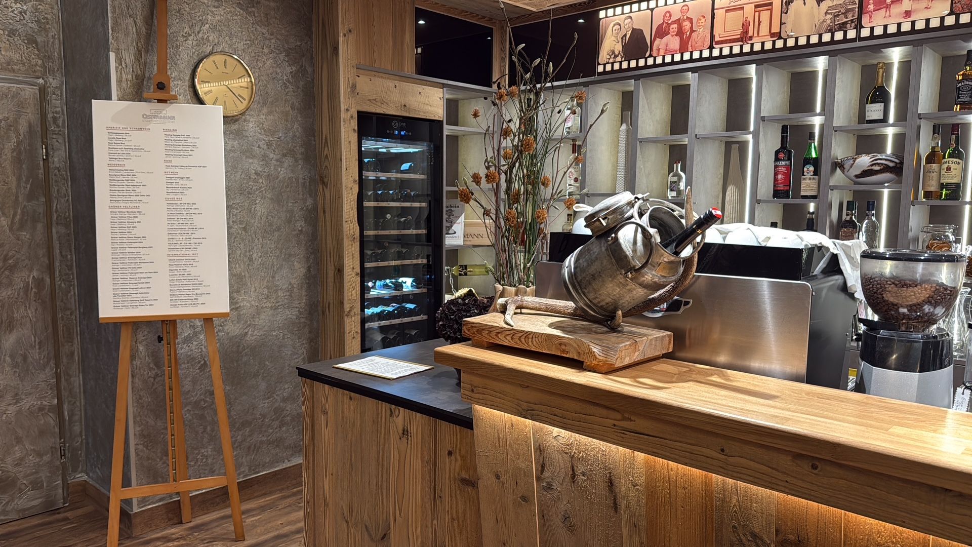 Pohled do interiéru restaurace s rustikálním pultem, lednicí na víno a jídelním lístkem na stojanu.