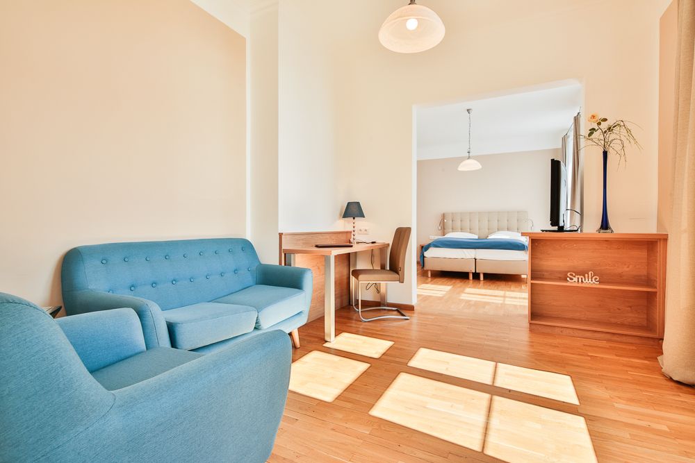 Světlý hotelový pokoj s modrým nábytkem a manželskou postelí.