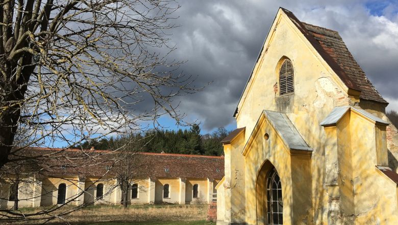 Žlutá budova charitního domu Mauerbach se zataženou oblohou.