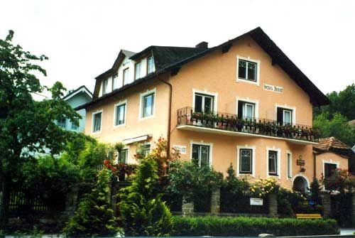 Oranžový patrový dům s dřevěným balkonem