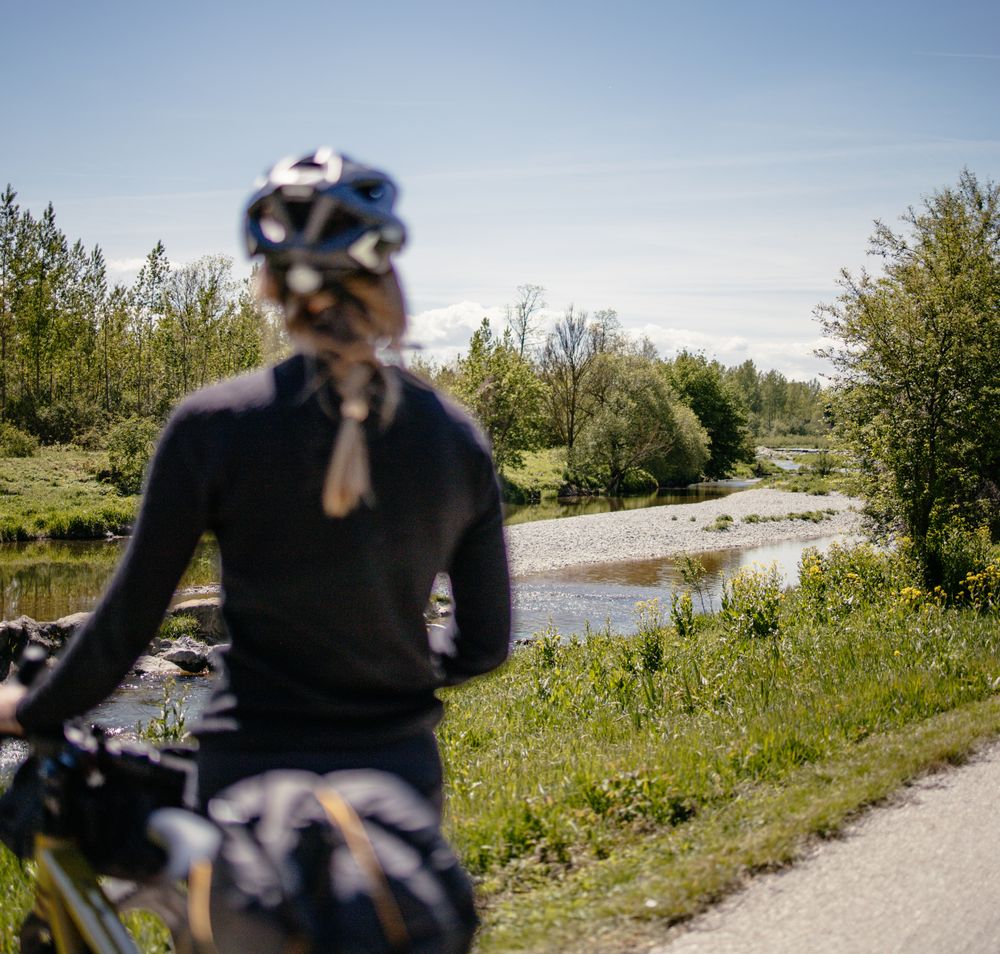 Ein sanfter Radweg schlängelt sich entlang des glitzernden Wassers, umgeben von üppigem Grün und blühenden Wiesen. Die frische Luft und die sanften Geräusche der Natur laden dazu ein, die Seele baumeln zu lassen und die Schönheit der Landschaft zu genießen.