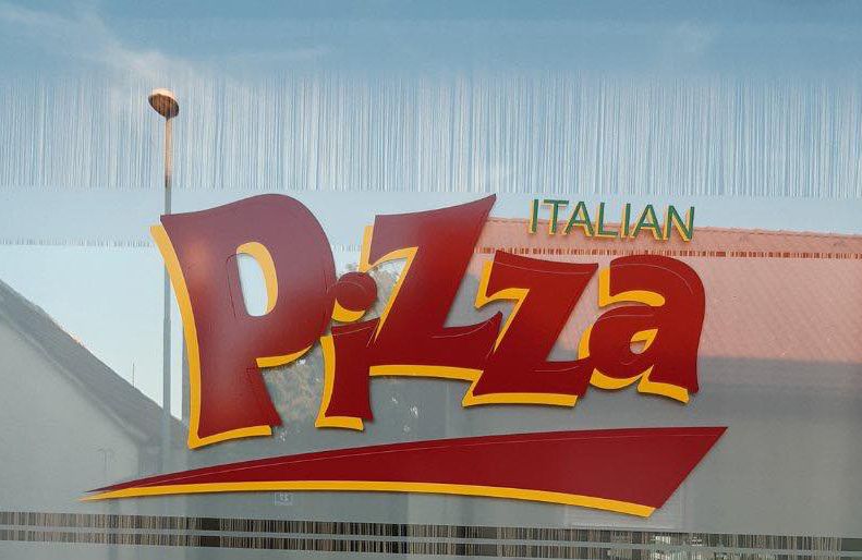 Okenní sklo s velkým červeným a žlutým nápisem "Italian Pizza".
