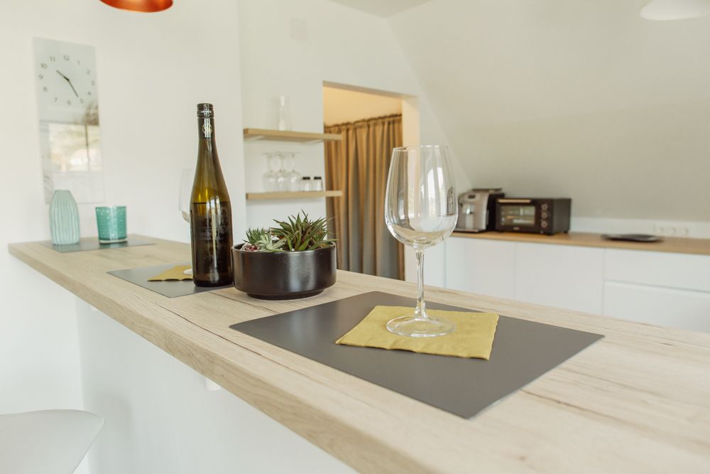 Moderní kuchyně s barovým pultem, sklenicí a lahví na víno.