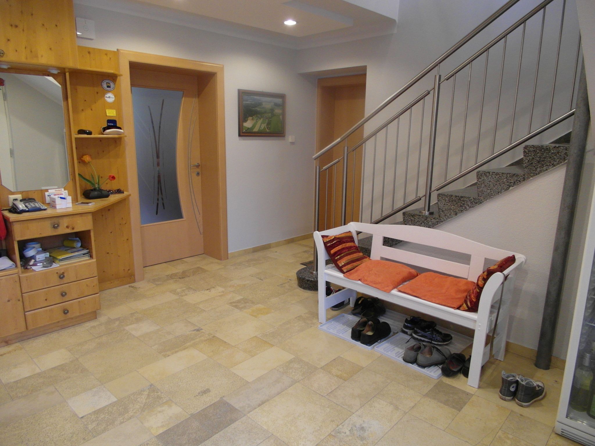 Vstupní prostor s dřevěnou komodou, lavicí s polštáři a schody.