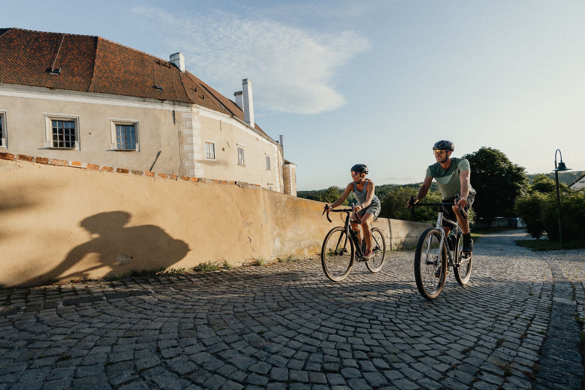 Dva cyklisté jedou po dlážděné cestě podél starých městských hradeb v Drosendorfu.