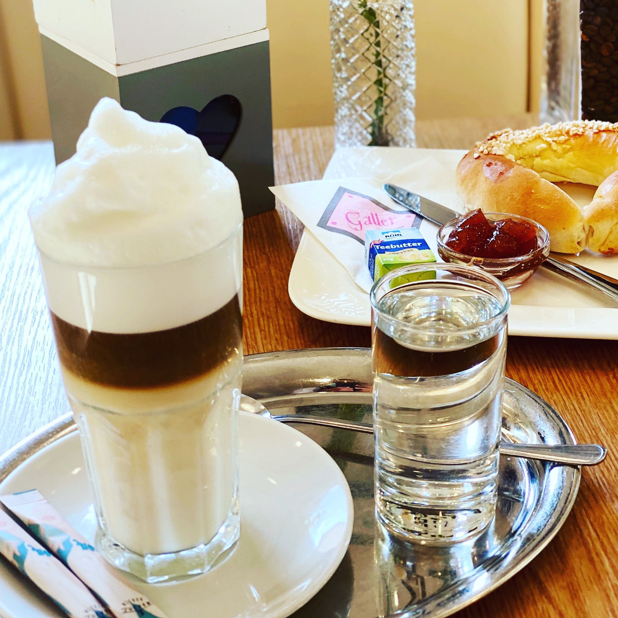 Snídaňový stůl s latte macchiato a brioškovými croissanty s marmeládou 