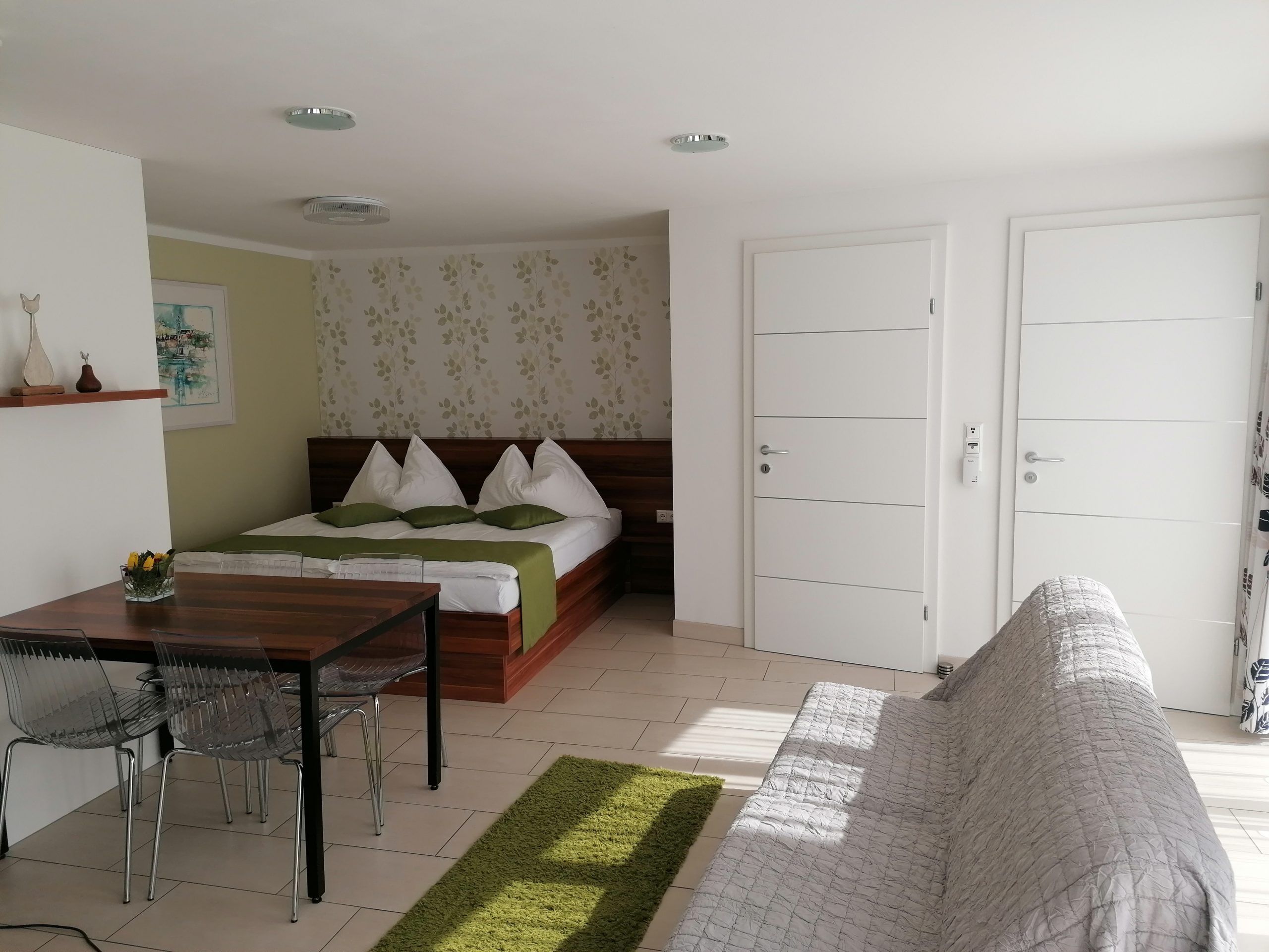 Pokoj s manželskou postelí a dvěma bílými vstupními dveřmi