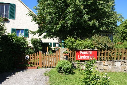 Dům se zahradou a nápisem "Pension Lindenhof" na dřevěném plotě.