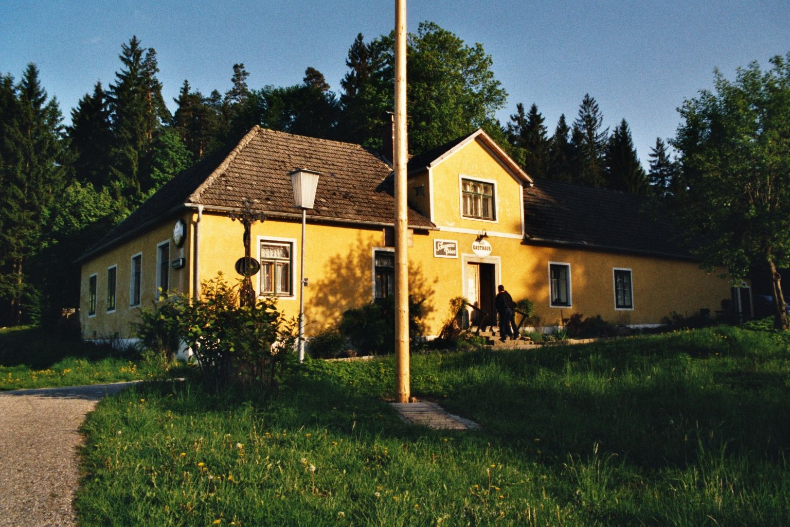 Žlutý hostinec ve venkovském prostředí se stromy v pozadí.