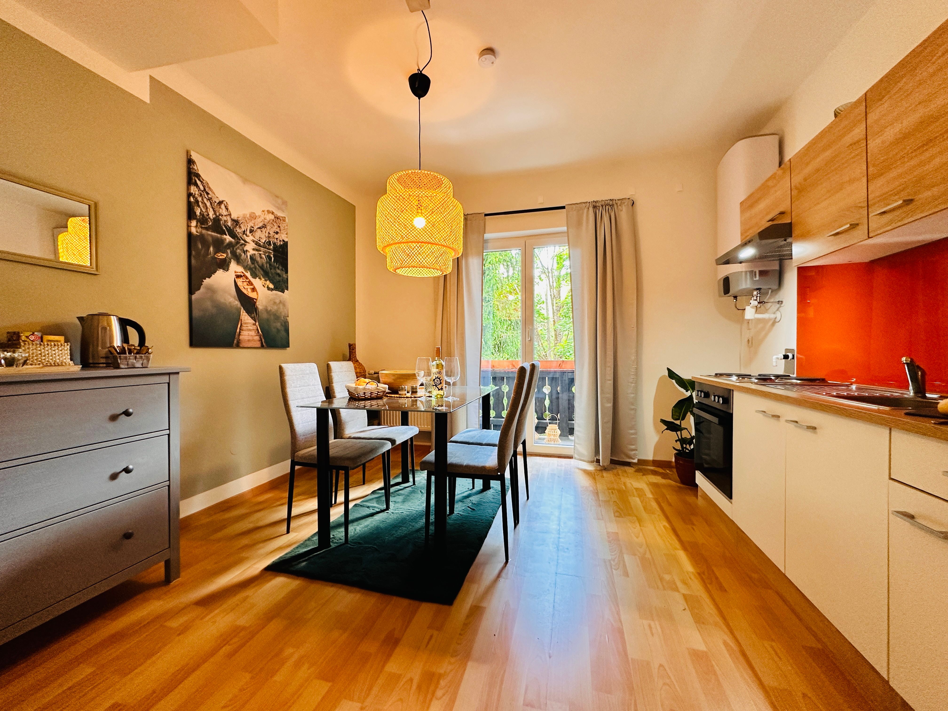 Útulný byt s jídelním stolem, židlemi, kuchyňským koutem a balkonem.