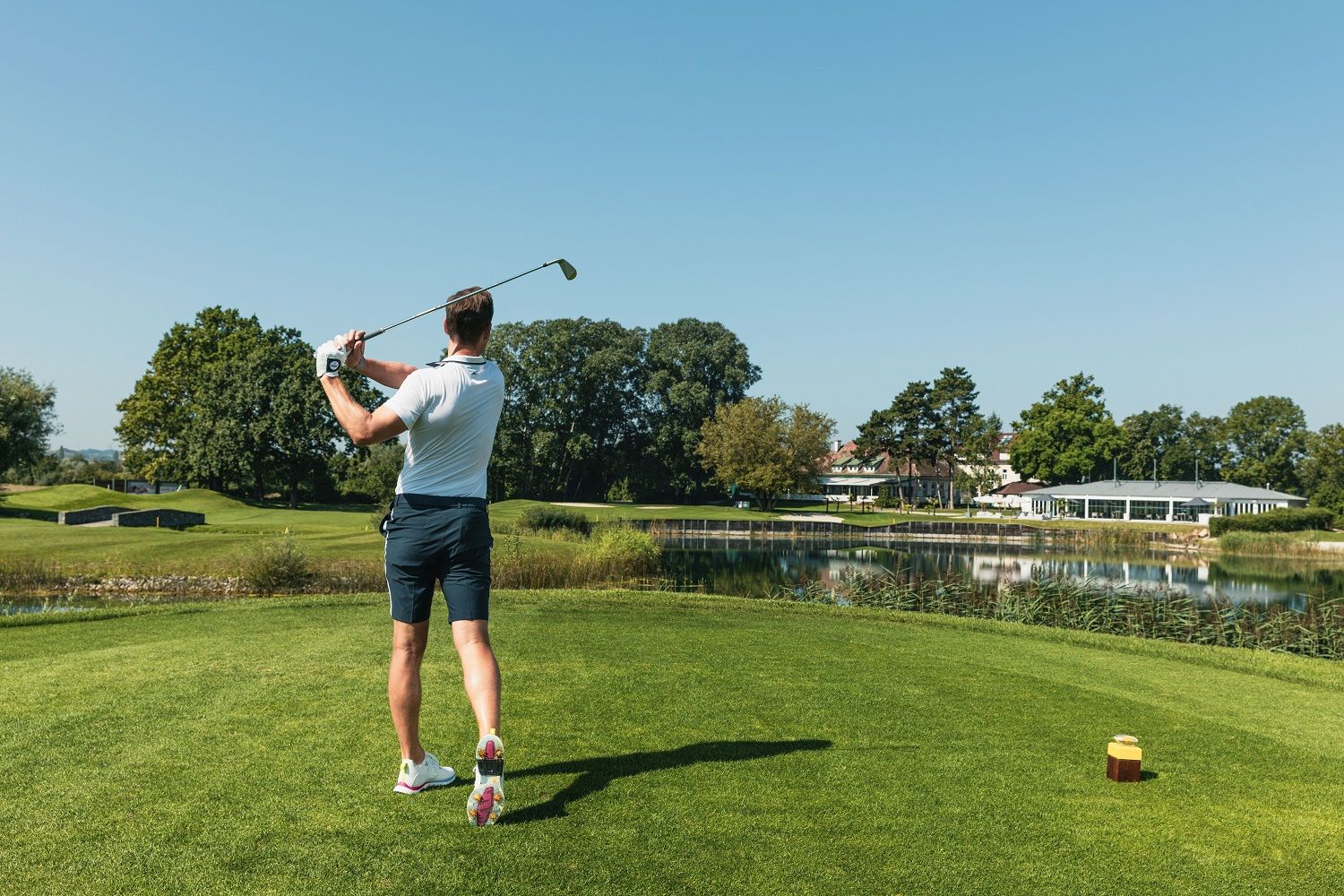 Golfista s golfovou holí v ruce, hrající golf.