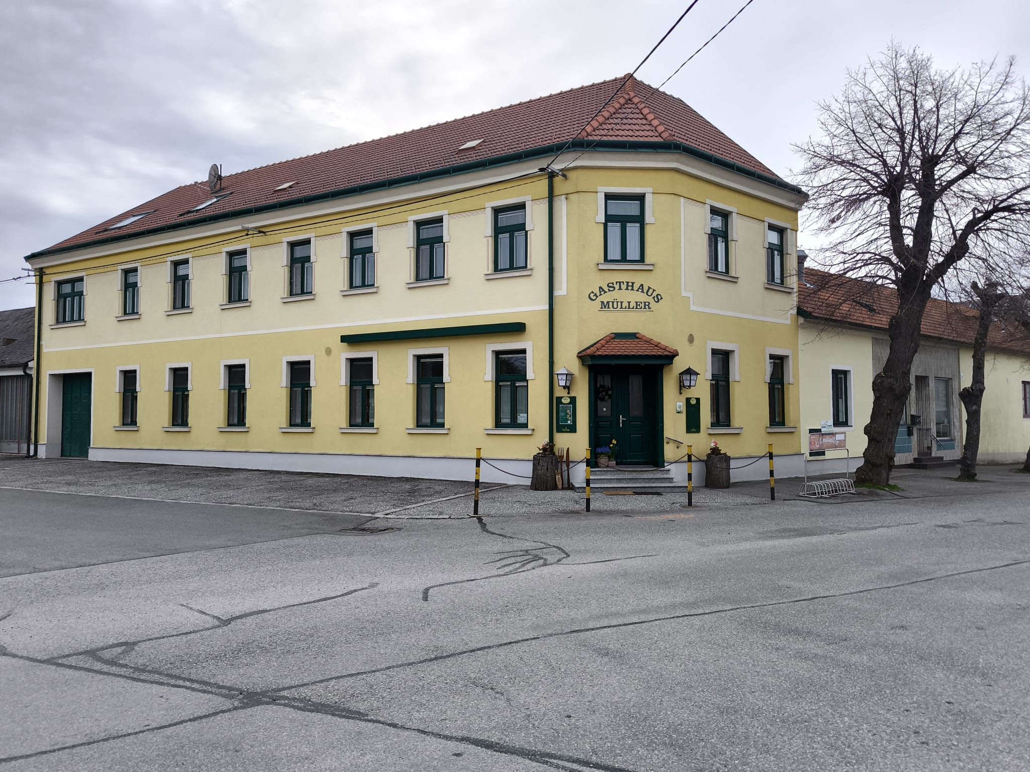 Žlutá dvoupatrová budova s nápisem "Gasthaus Müller".