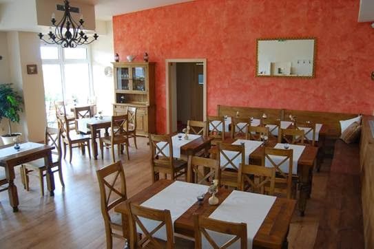 Pohled do interiéru restaurace s dřevěným nábytkem a červenými stěnami.