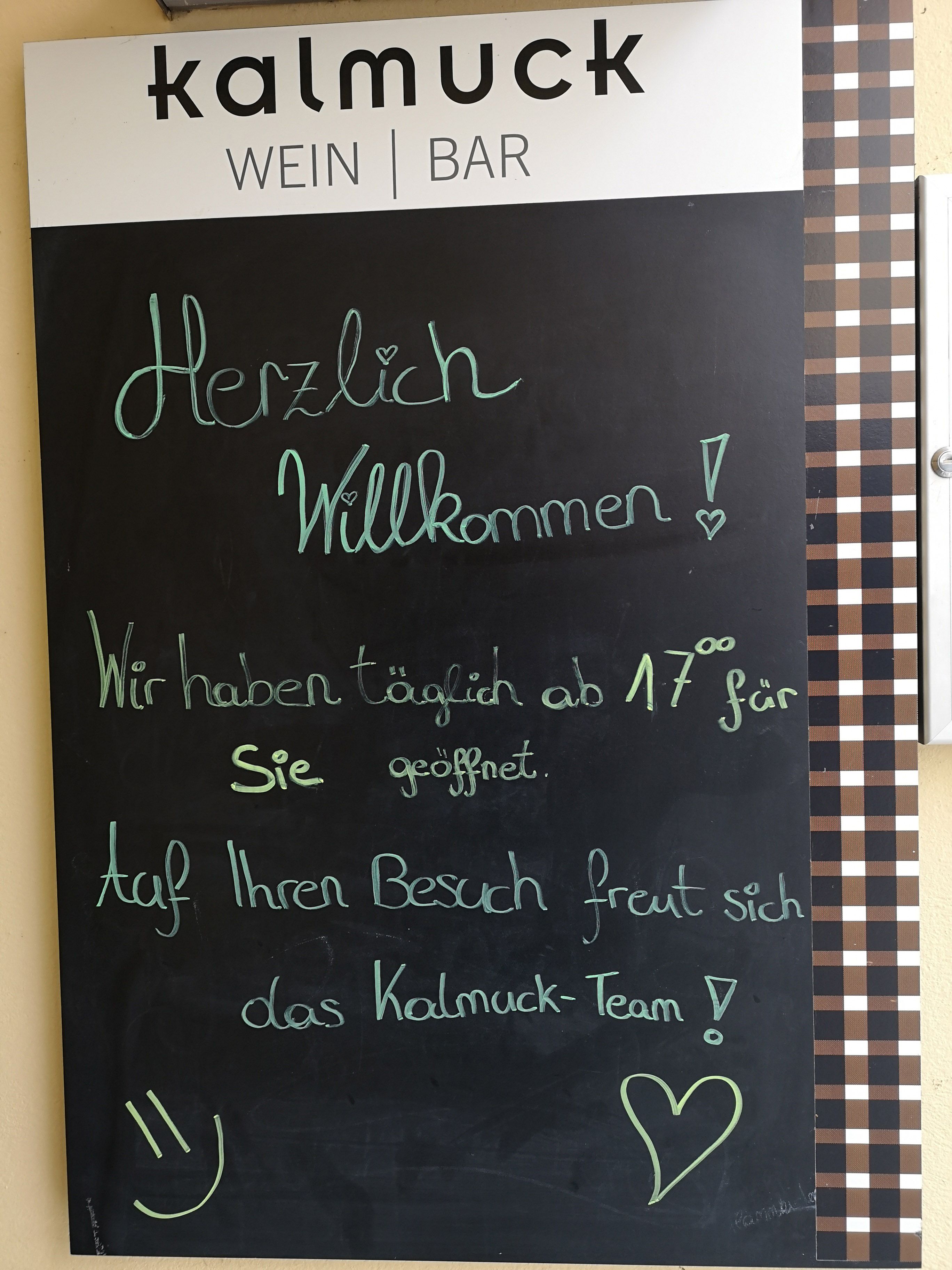 Deska s uvítacím textem před vinárnou Kalmuck.