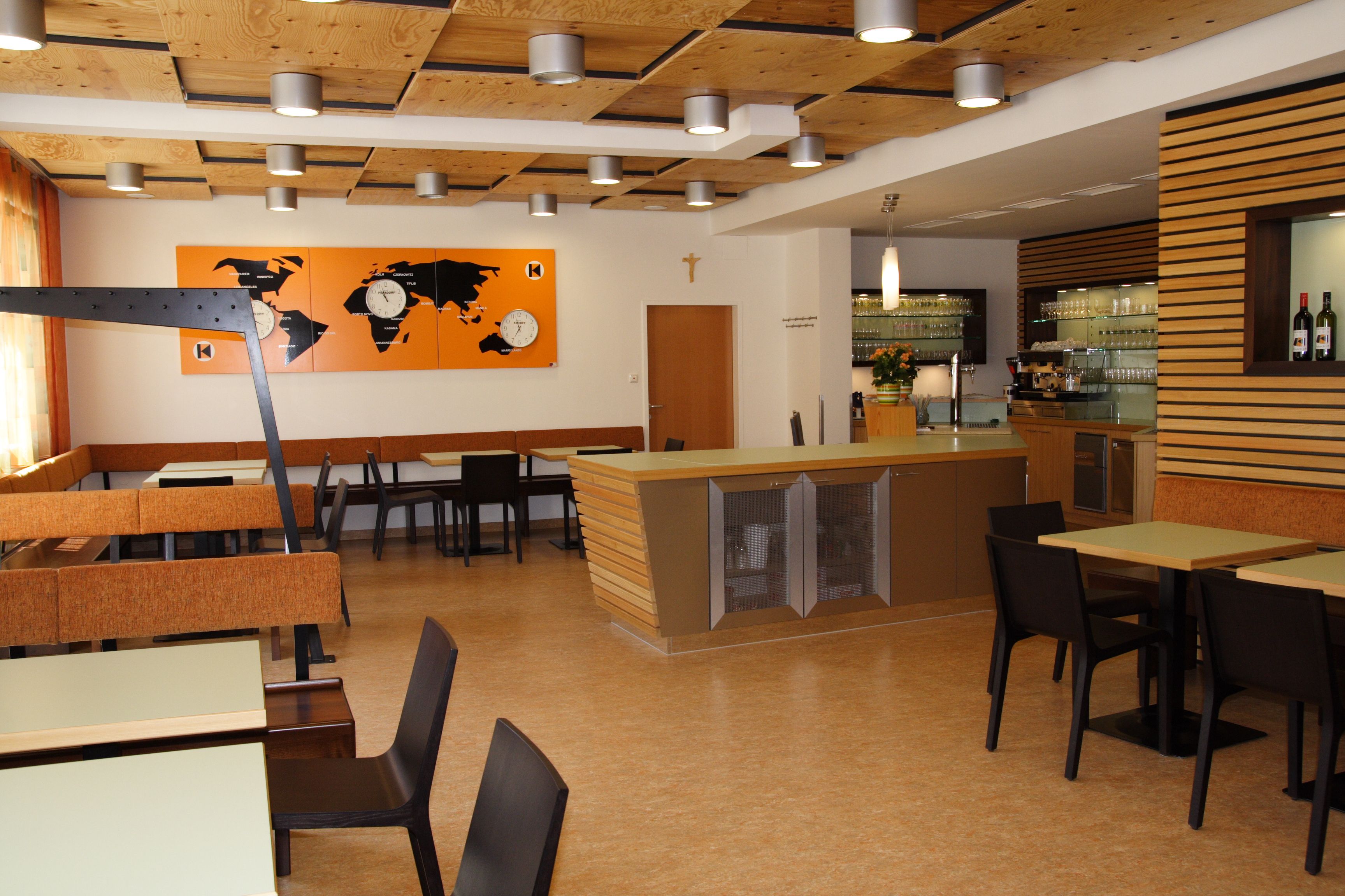 Pohled do interiéru moderní restaurace s dřevěnými prvky a dekorem mapy světa.