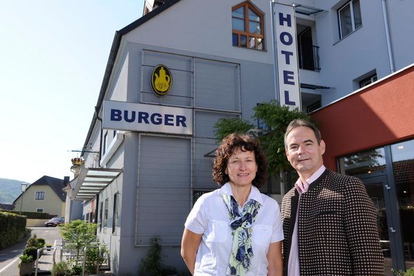 Muž a žena stojí před budovou s nápisem "Hotel Burger".