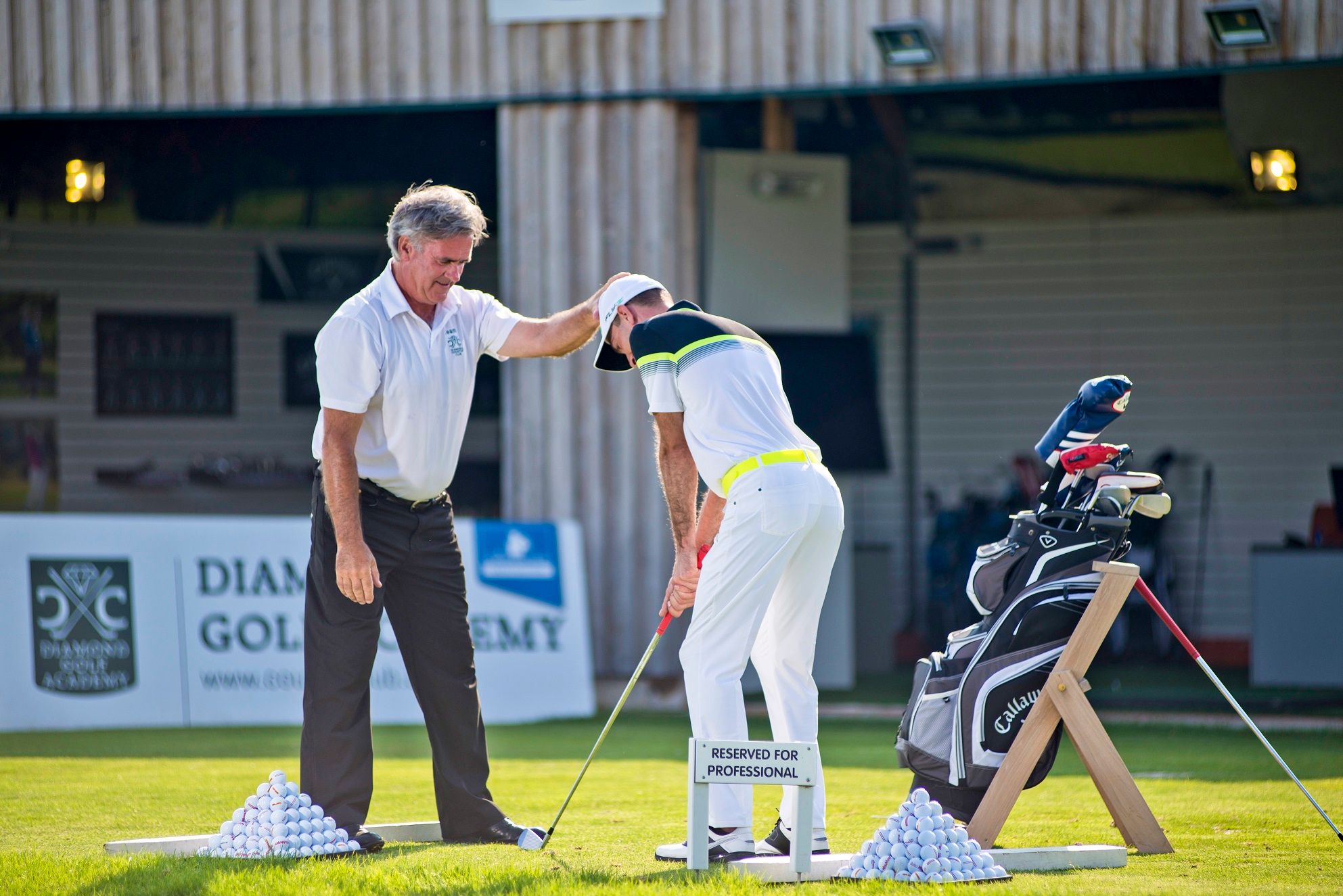 Golfový instruktor dává pokyny studentovi na cvičném hřišti v Diamond Golf Academy.