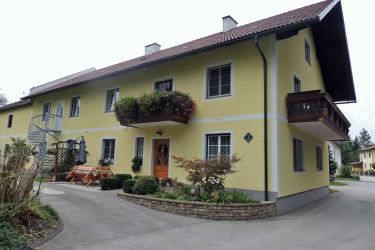 Žlutý dvoupodlažní dům s balkonem a zahradou.