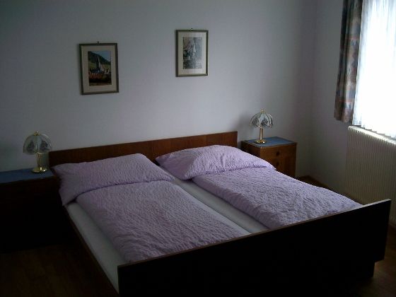 Jedna ložnice s manželskou postelí, dvěma nočními stolky a dvěma stolními lampami.