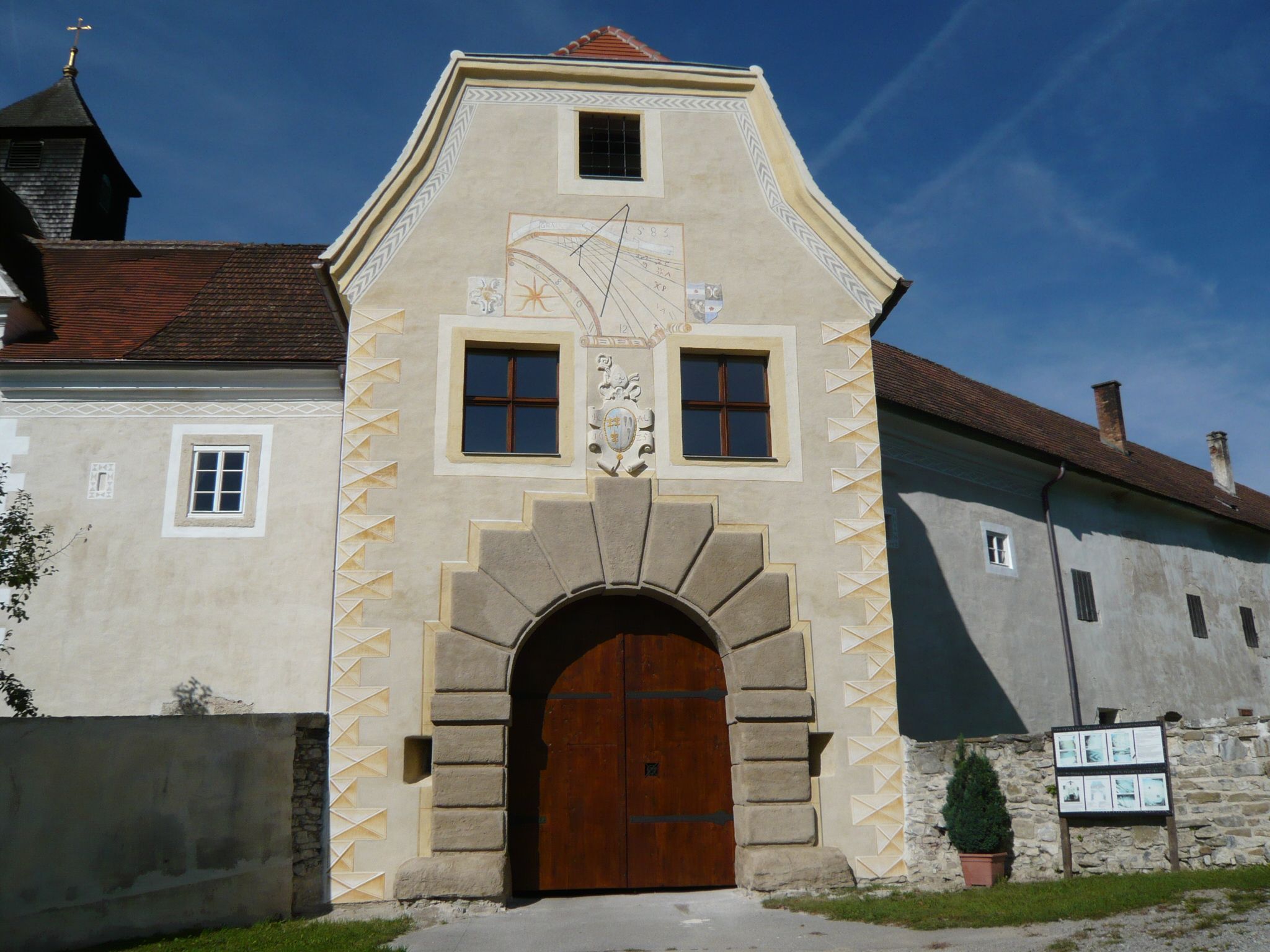 Vstupní brána do hradu Kreisbach se slunečními hodinami a erbem.