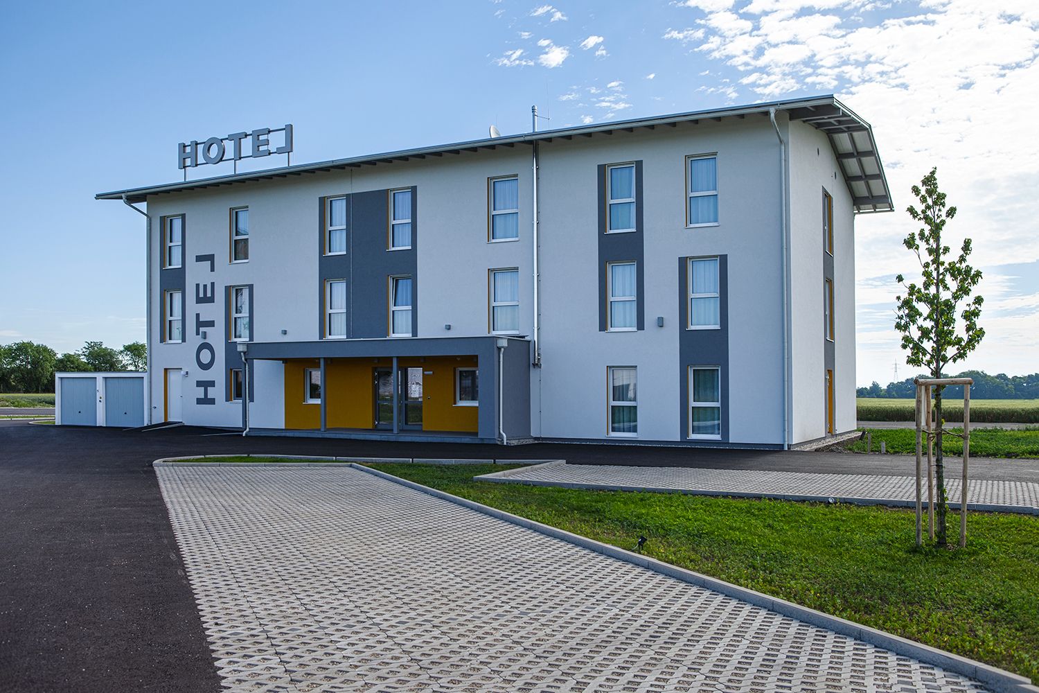 Pohled na hotel zvenčí s parkovištěm.