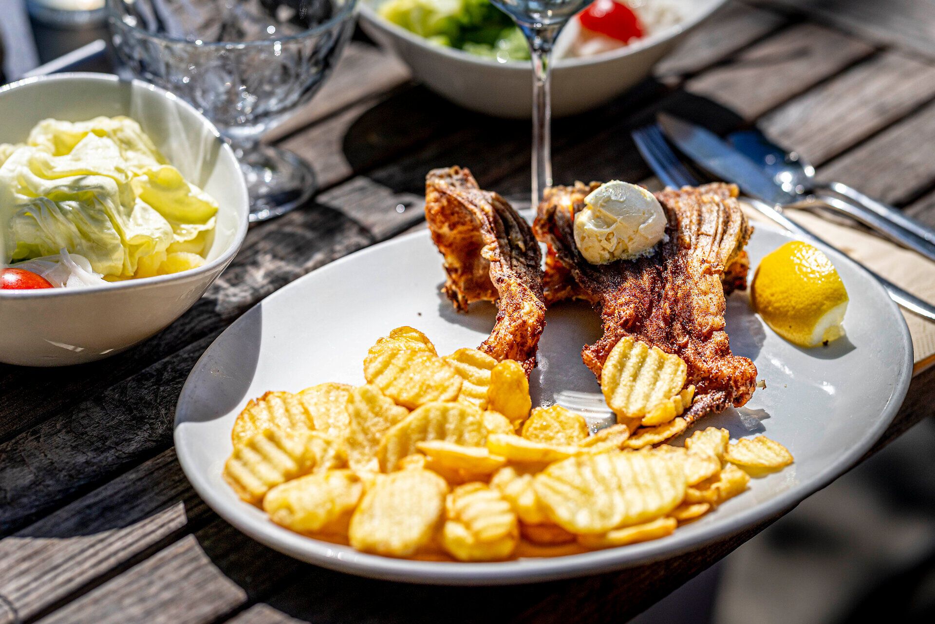 Rybí pokrm a plátky brambor na bílém talíři. 