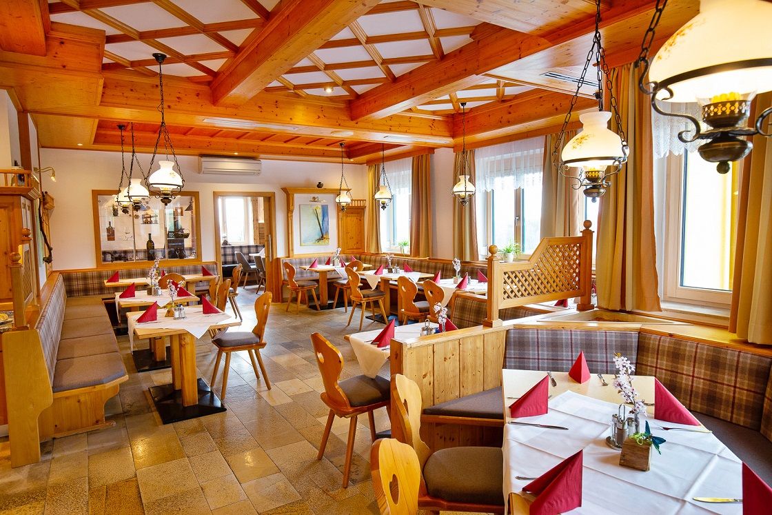 Útulná restaurace s dřevěným nábytkem a prostřenými stoly.