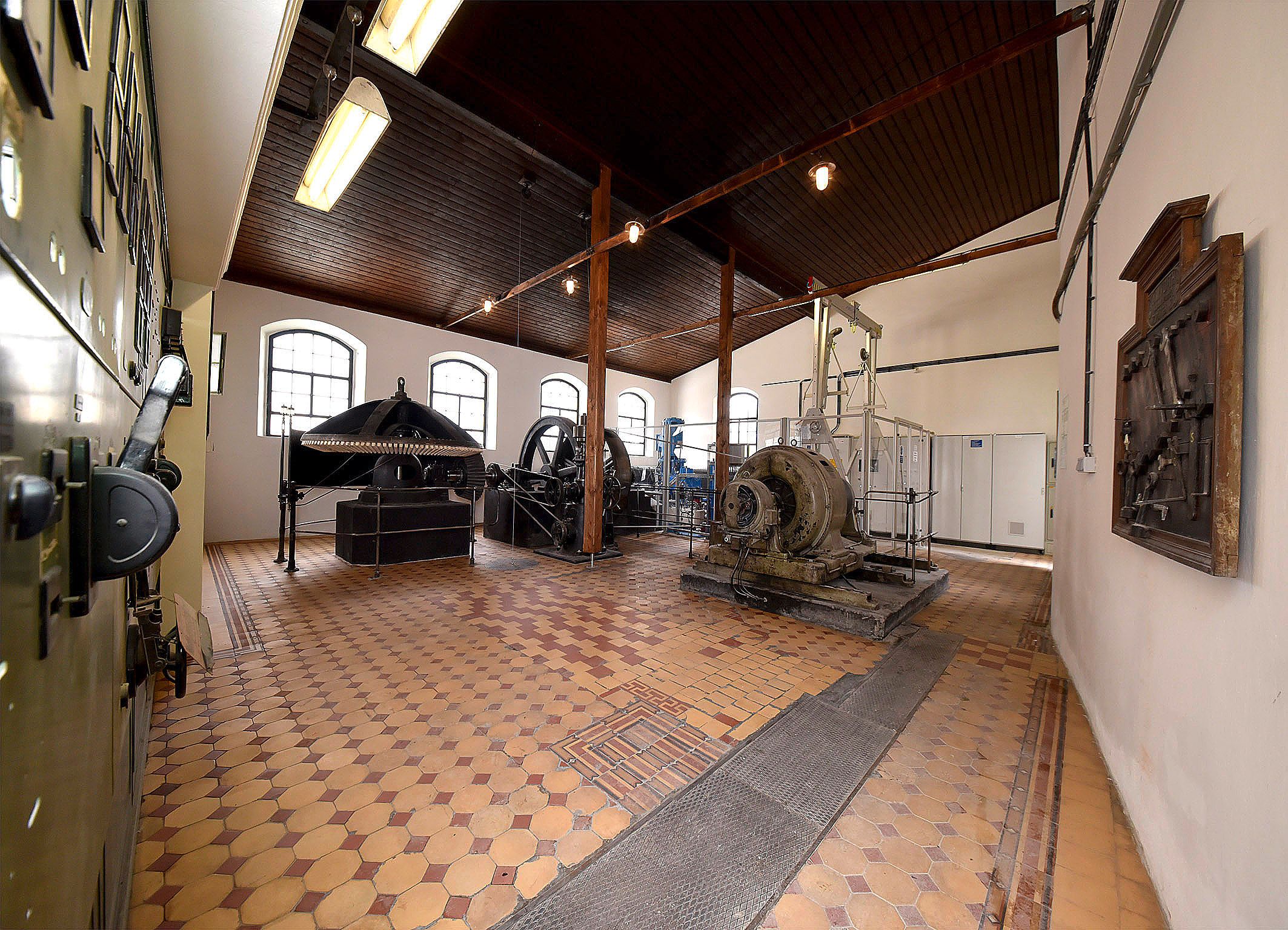 Pohled do interiéru historické elektrárny se stroji a zařízením.