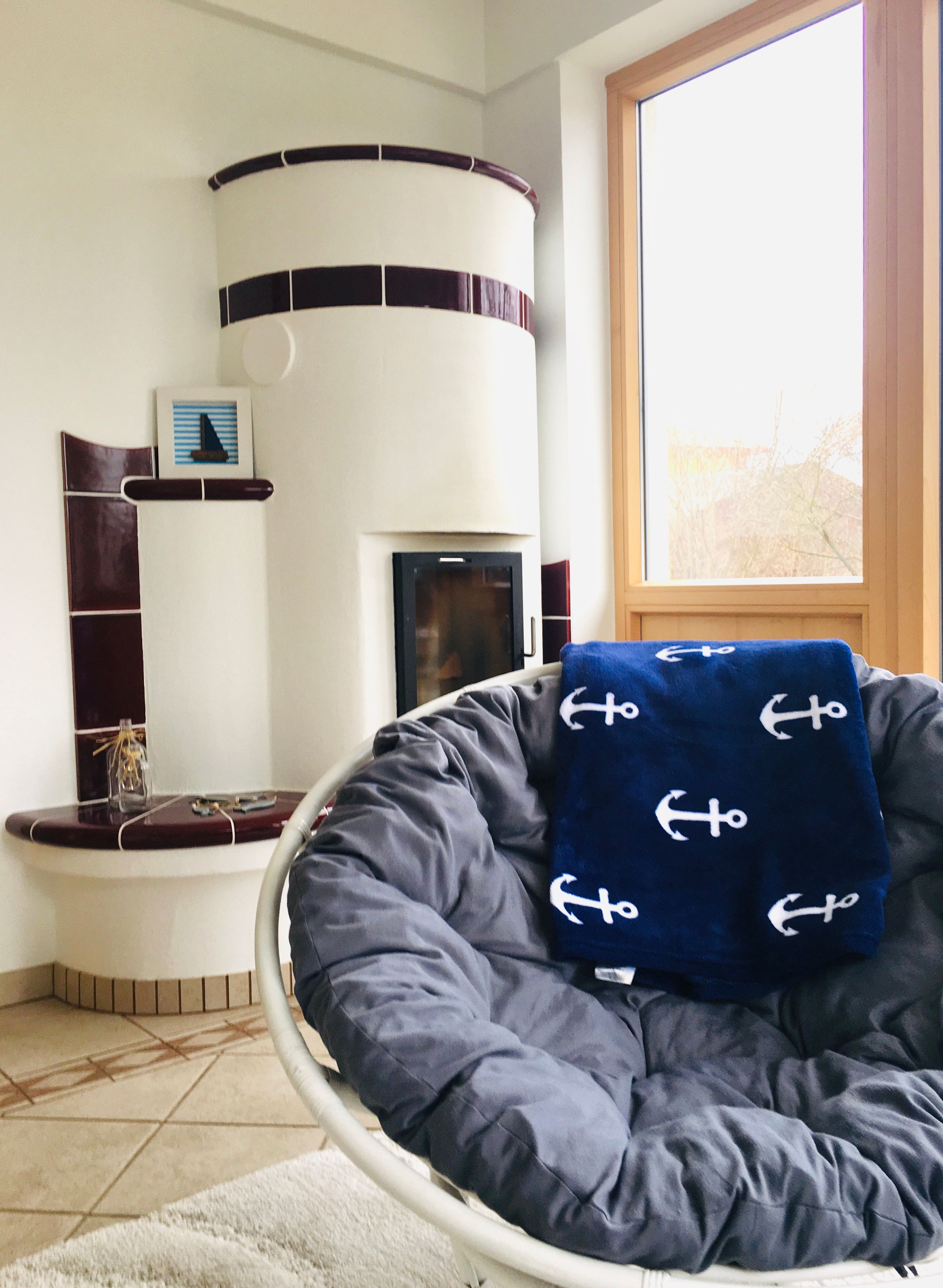 Útulný obývací pokoj s kachlovými kamny a křeslem.