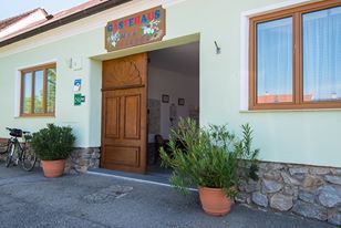 Vchod do budovy s dřevěnými dveřmi a rostlinami v květináčích.