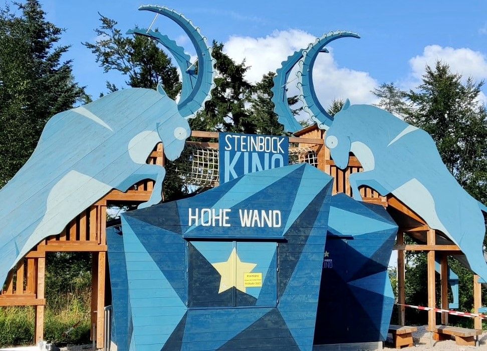 Vstup do kina Steinbock v přírodním parku Hohe Wand se siluetami modrých kozorožců.