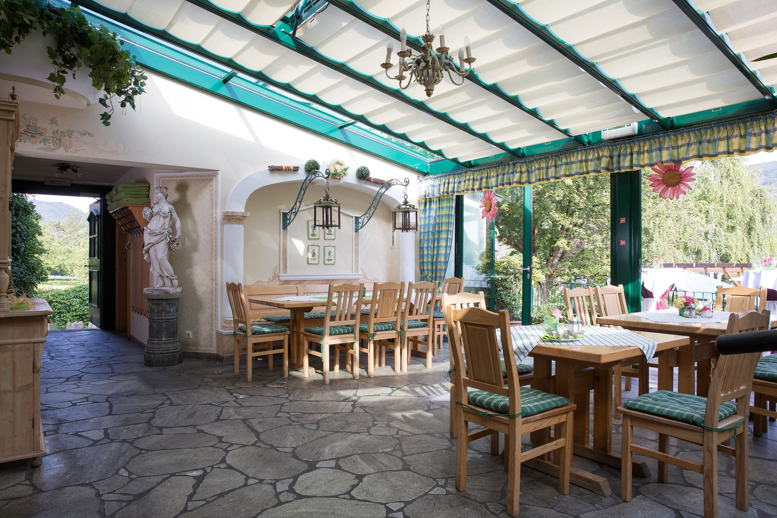 Pohled do interiéru vinárny s dřevěným nábytkem, kamennou podlahou a skleněnou střechou.