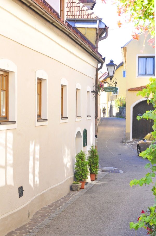Úzká ulička ve Wachau se žlutými domy a lucernou.