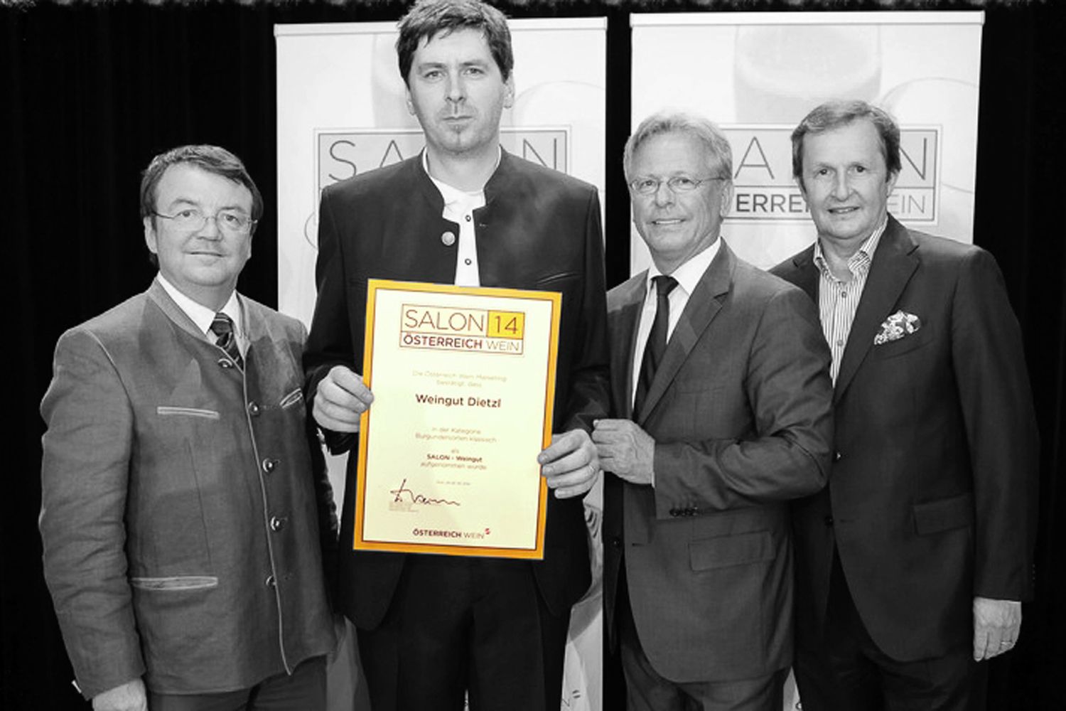 Čtyři muži v oblecích drží před kamerou Ocenění s nápisem "Salon 14 Austria Wine".