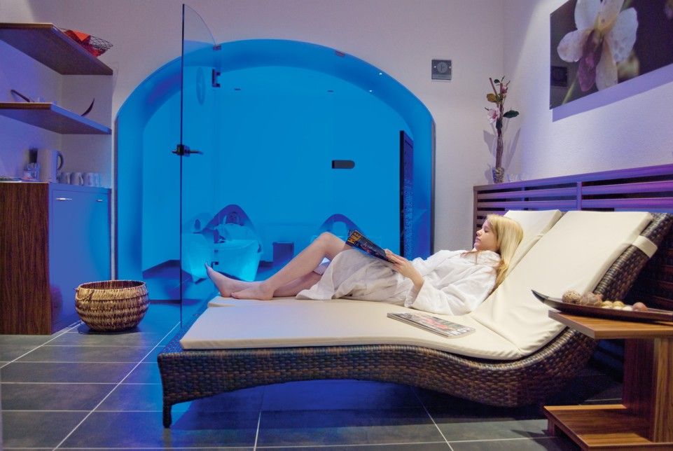 Žena odpočívá na lehátku ve wellness zóně s modrým osvětlením.