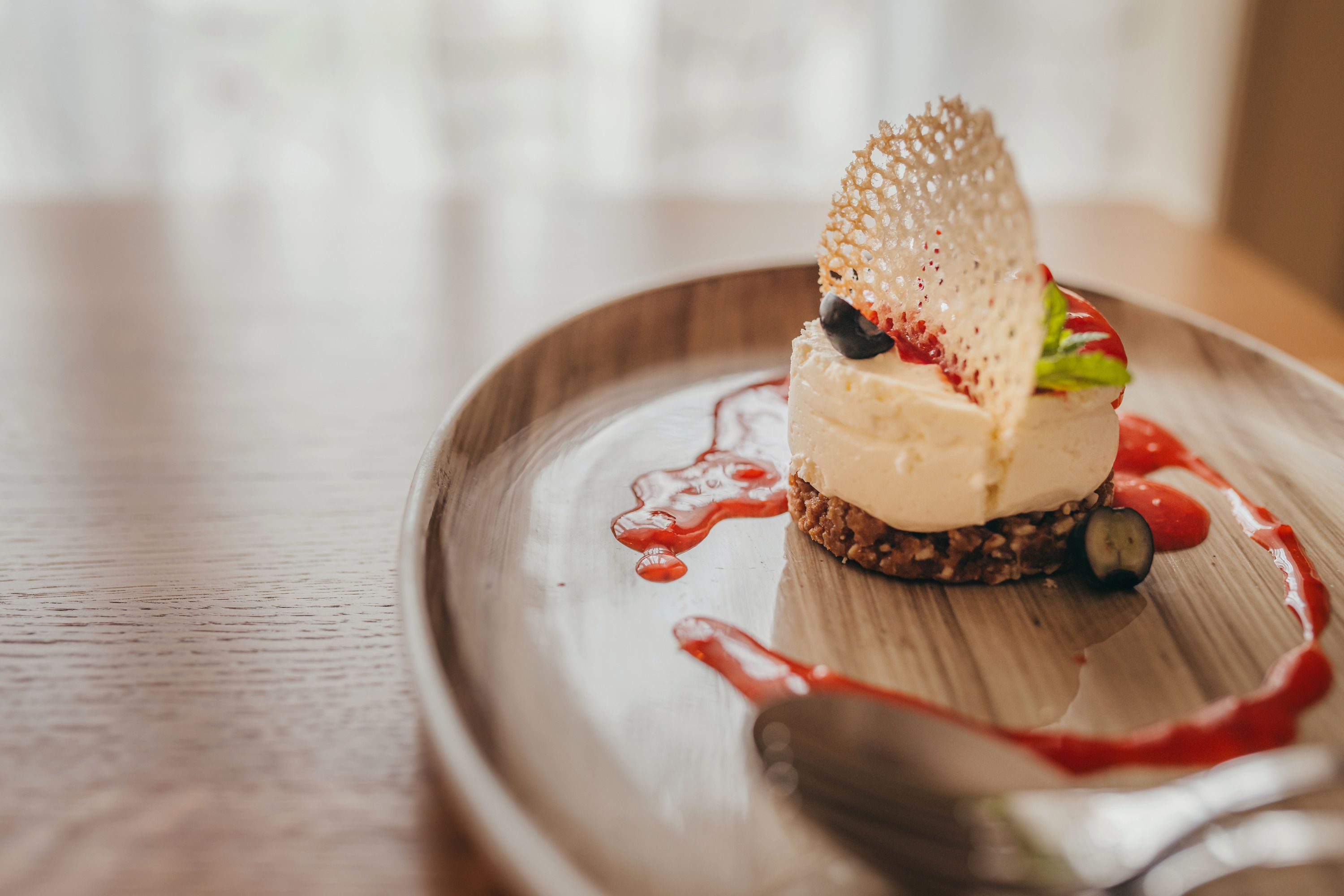 Mini tvarohový koláč s jahodovým coulis podávaný na talíři.