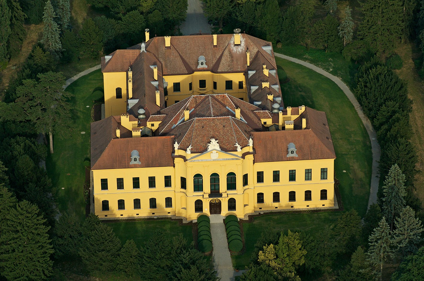 Letecký pohled na zámek Eckartsau obklopený stromy a zahradami.