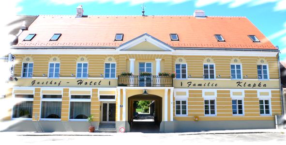 Žlutá budova s červenou střechou a nápisem "Gasthof-Hotel Familie Klapka".